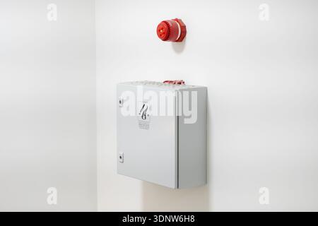 Vibrant red fire alarm horn and grey control panel labeled for smoke mechanical ventilation, mounted on a white wall, promoting urgent emergency readi Stock Photo