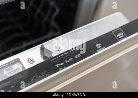 Close-up of an open dishwasher door panel displaying MY TIME, 30min, 90min, ECO, ExtraPower, AUTO wash programs for efficient home kitchen use Stock Photo