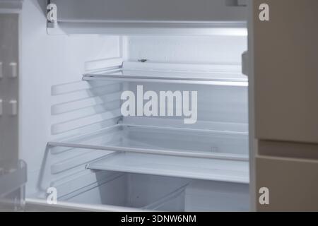Brightly lit inside of a modern, vacant refrigerator, showcasing pristine glass shelves, perfect for representing fresh start, food storage, or househ Stock Photo