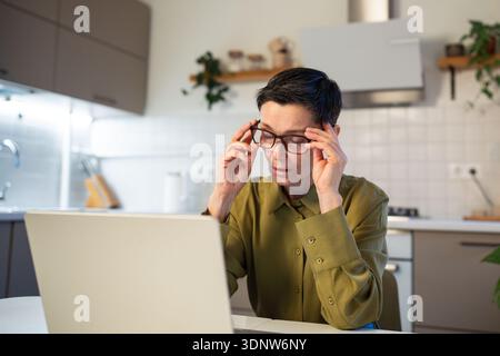 Stressed overworked senior businesswoman with burnout works on laptop, feeling exhausted and tired Stock Photo