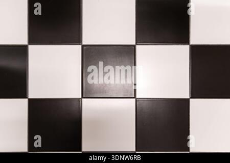 Close-up view of a high-contrast checkerboard pattern of black and white tiles, ideal for classic flooring, wall decor, or abstract graphic design ele Stock Photo