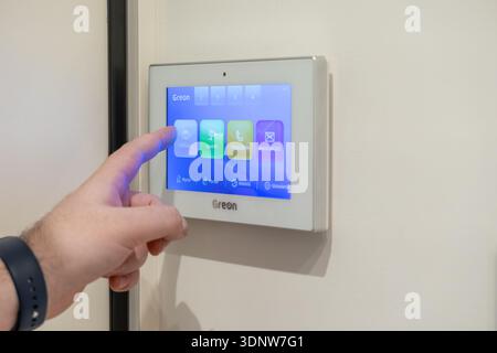 Krakow, Poland - November 30, 2025: Close-up of a human finger activating a smart home touchscreen panel, ensuring enhanced residential security and e Stock Photo