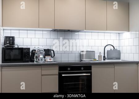 Krakow, Poland - November 30, 2025: Elegant modern kitchen with clean lines, beige cabinets, white subway tiles, and essential appliances creating an Stock Photo