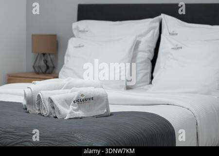 Krakow, Poland - November 30, 2025: A close-up view of freshly laundered white towels with EXCLUSIVE APARTHOTEL logo, neatly folded on a comfortable h Stock Photo