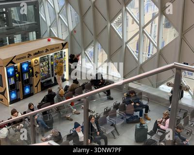 Poznan, Poland - November 30, 2025: Overhead view of various travelers resting in a bright, spacious airport or train station terminal, utilizing conv Stock Photo