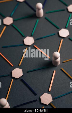 A conceptual model of an organizational structure is displayed using wooden peg figures, hexagons, and colored sticks to represent nodes and connectio Stock Photo