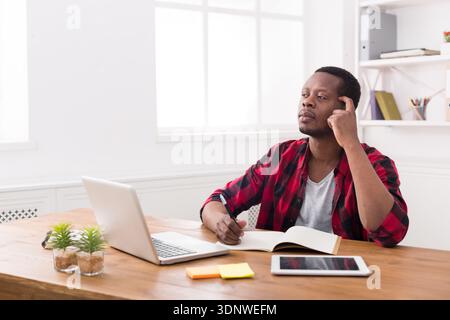 African american businessman using laptop and making notes Stock Photo