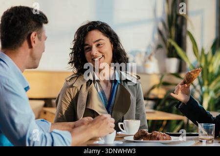 Coworkers smiling and discussing during coffee break Stock Photo