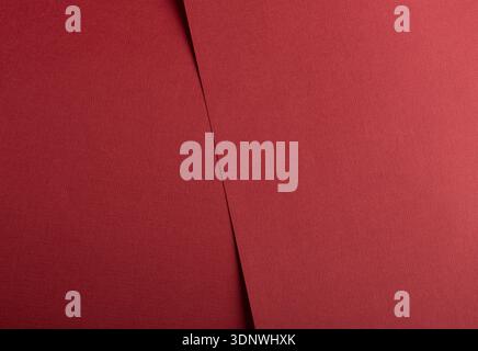 Red textured paper background with vertical overlap and straight edge. Matte grainy surface and muted warm tone. Clean minimal backdrop for modern lay Stock Photo