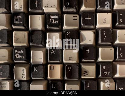 vintage computer keyboard keys with worn letters symbols and dust texture. Retro input device surface, nostalgic background detail. Stock Photo