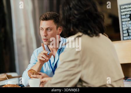 Coworkers discussing business during coffee break with croissants Stock Photo