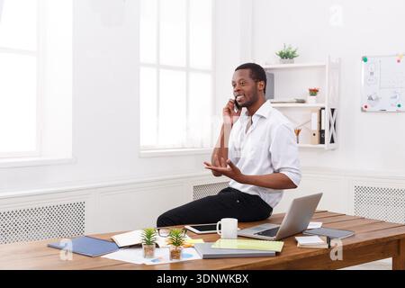 Young black businessman with mobile in modern white office Stock Photo