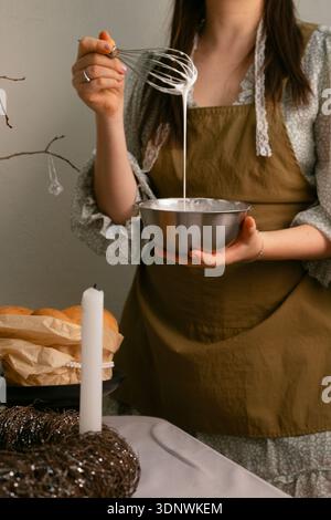 Traditional Easter celebration preparing glaze for Easter cake with eggs and candles Stock Photo