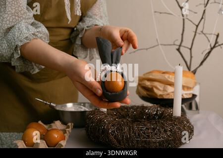 She carefully arranges dishes, lights candles, and paints eggs, filling the home with Easter spirit and cozy warmth. Stock Photo