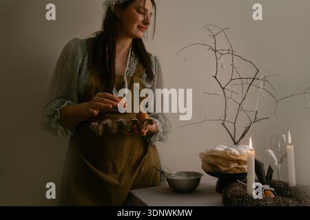 Woman setting the Easter table with care and joy, filling the home with light warmth and festive coziness. Stock Photo