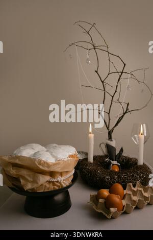 Warm Easter moment with cake in white icing, eggs in tray, candles, and twig wreath filling the home with coziness and light. Stock Photo