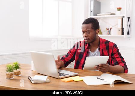 Pensive young black happy businessman in office, work with laptop Stock Photo
