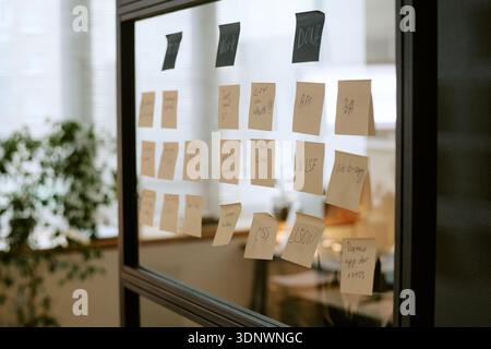 Organizing Business Workflow Using Sticky Notes on Glass Wall in Office Stock Photo