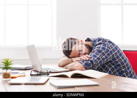 Overworked exhausted manager sleeping on table after working day Stock Photo
