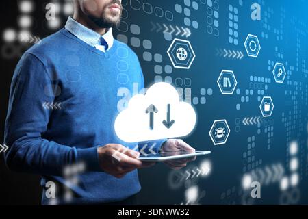 Man using tablet for cloud data exchange in digital environment with various icons Stock Photo