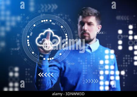 Man interacts with digital cloud interface in a modern workspace at evening time Stock Photo