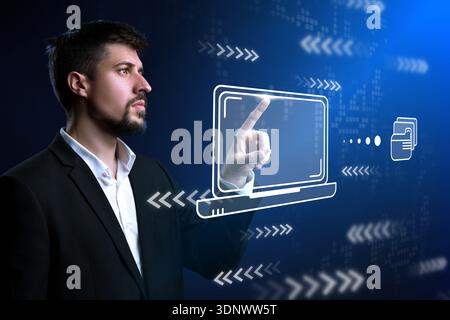 Man interacts with holographic laptop display in modern tech environment Stock Photo