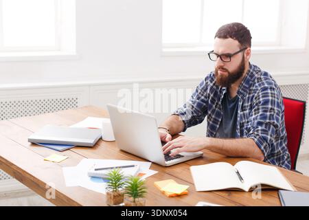 Young businessman working with laptop in modern white office Stock Photo