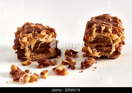 Close-up of a broken chocolate caramel bar with nuts on a white background. Stock Photo