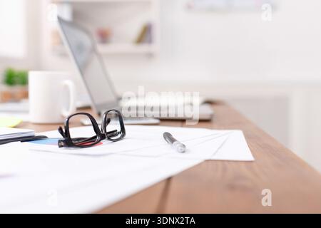 Side view of office desk with glasses, laptop and other items Stock Photo