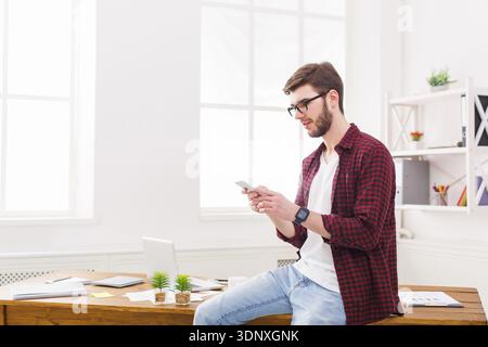 Relaxed young businessman using mobile in office Stock Photo