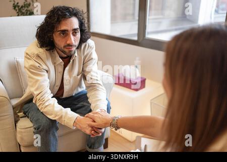 A patient engages in a therapy session, receiving support in a psychological clinic setting. The caring interaction highlights the importance of menta Stock Photo