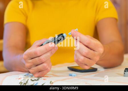 A close-up view of a person handling an insulin pen and testing supplies. This image depicts the important routine of managing diabetes through blood Stock Photo