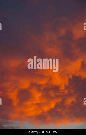 Stunning vibrant red clouds fill the dramatic sunset sky over Gran Canaria. The glowing hues create a visually captivating scene, illustrating nature Stock Photo