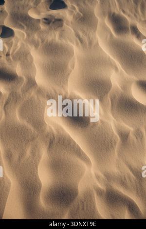 Close up of textured sand patterns formed by the wind in Denmark. The image captures the delicate ripples and shadows on the sand, showcasing nature i Stock Photo