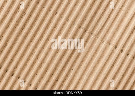 A close-up view of corrugated cardboard displaying its distinct brown texture and ridged pattern. Perfect for eco-friendly design projects and packagi Stock Photo
