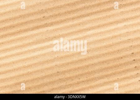 A close-up of corrugated kraft paper with a natural brown hue, featuring subtle lines and shadows. The texture showcases its characteristic roughness Stock Photo