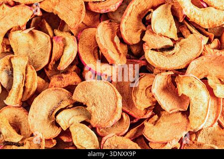 Top view of various dried apple slices forming a natural pattern with textures and hues of orange and red. The dried fruit creates a rustic and textur Stock Photo