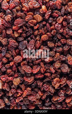 Top view of dried raisins in rich brown hues. The glossy, wrinkled surface of these sweet, dried grapes creates a visually appealing pattern. Stock Photo