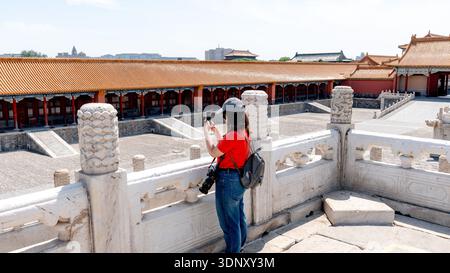 A visitor photographs the historic architecture of the Forbidden City in Beijing, China. The striking red and gold colors of the ancient imperial pala Stock Photo