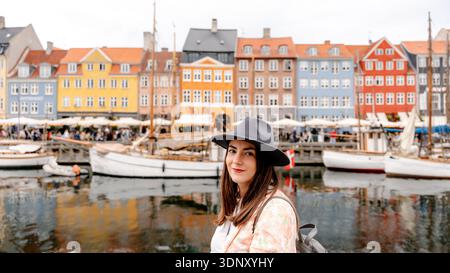 A visitor enjoys the vibrant atmosphere of Nyhavn in Copenhagen, Denmark, with colorful historic buildings and traditional boats along the picturesque Stock Photo