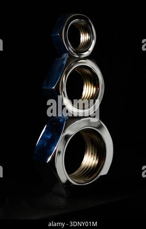 Large industrial nuts stacked with a dark background Stock Photo
