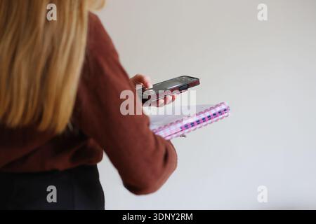 Female freelancer multitasking with phone and notebook. Time management, organization and remote work concept. Stock Photo