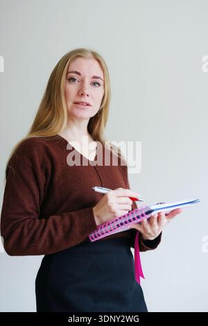 Female professional writing notes and planning tasks indoors Stock Photo