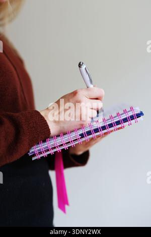 Female hands holding notebook and writing with pen. Education, journaling and work organization concept with copy space. Stock Photo