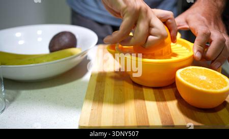 Juicing oranges on kitchen table. Casual kitchen setup for extracting fresh orange juice Stock Photo
