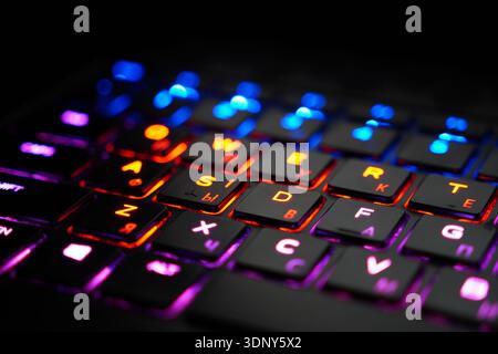 Close-up macro photograph of illuminated gaming keyboard with vibrant RGB backlighting in blue, red, purple, and yellow colors creating colorful bokeh Stock Photo