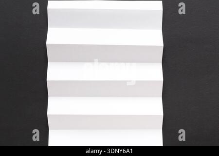 White folded sheet of paper on black background Stock Photo