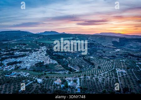Sunset Over Olive Groves and Terraced Hills With A Hillside Village In A Peaceful Rural Landscape, Setenil de las Bodegas, Spain Stock Photo