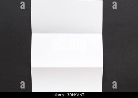 White folded sheet of paper on black background Stock Photo