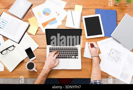 Top view businessman using laptop with analyzing investment charts on the office desk. Stock Photo